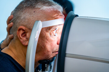 Senior man leaning the head on scanner to check glaucoma