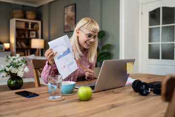 Young woman economist economy expert working in home office having video call on laptop with...