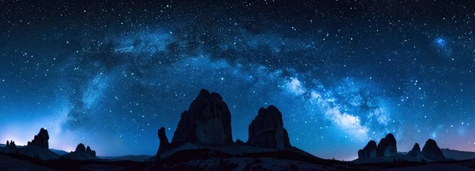 Poster Silhouettes of rock formations against the night sky with stars and milky way © EMRAN