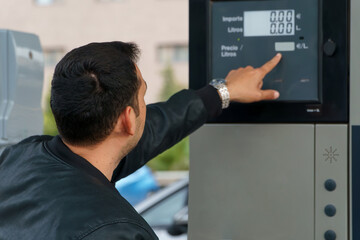 Man using an automatic teller machine to check the amount of fuel - obrazy, fototapety, plakaty
