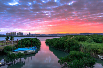 Fototapeta na wymiar Fiery clouds of winter sunset over the Tamsui river at Zhongshe small dock in the outskirts of Taipei city, Taiwan.
