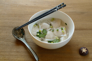 a bowl of wonton soup on wooden table