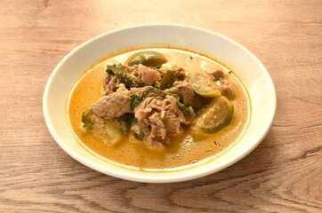spicy boiled slice pork meat with eggplant in coconut milk green curry soup on plate