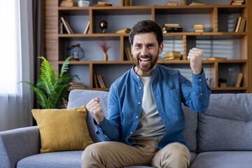 Man sitting on a couch at home, celebrating success