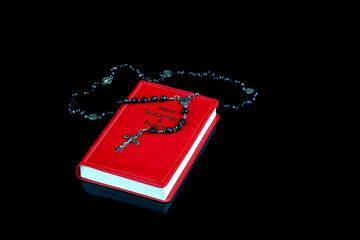 Rosary with New Testament Isolated on a Shiny Black Surface - 763200295