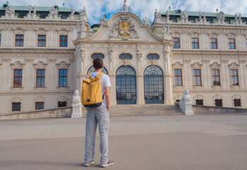 male tourist traveling in Austria, capital city Vienna. summer male solo trip to Europe, happy young man walking in park near Belvedere palace complex in Baroque style. - obrazy, fototapety, plakaty