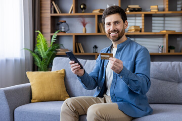 Smiling man shopping online with credit card at home