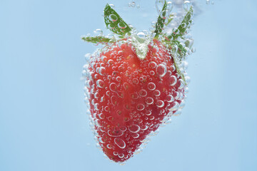 Macro photograph of a strawberry in sparkling mineral water. Close up on details of a berry and water bubbles. 