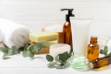 Beautiful spa composition on a wooden background with eucalyptus leaves. Beauty and fashion spa concept with body cream, scrub, mask, essential oil and sea salt.Cosmetic product. Copy space.