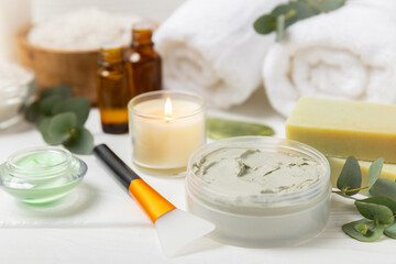 Beautiful spa composition on a wooden background with eucalyptus leaves. Beauty and fashion spa concept with body cream, scrub, mask, essential oil and sea salt.Cosmetic product. Copy space.