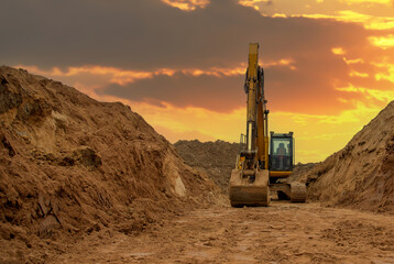 Excavator digs a large trench for pipe laying. Backhoe during earthmoving at construction site. Earth-moving heavy equipment