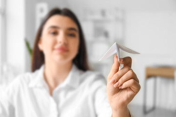 Young businesswoman with paper plane in office, closeup