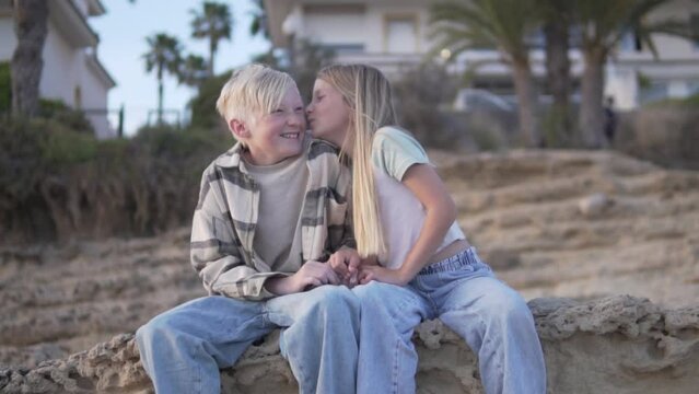 Children is friendship. A little girl with long white hair kisses a blond boy on the cheek