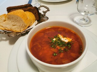 A plate of orange borscht with bread on the table