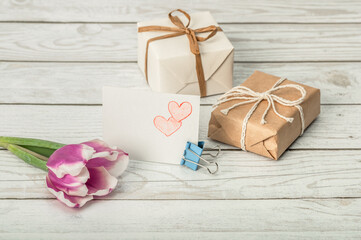 Tulip, card with drawn hearts and gift boxes on a wooden background. DIY greetings for Mother's Day, Valentine's Day, Birthday and Women's Day.