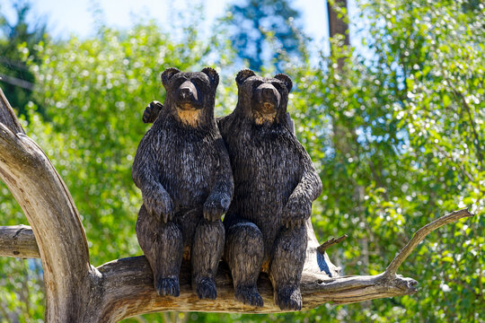 Two wooden bears sitting on branch at Predjama castle on a sunny summer day. Photo taken August 11th, 2023, Predjama, Slovenia.