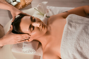 Young woman getting facial massage in dark spa salon, closeup