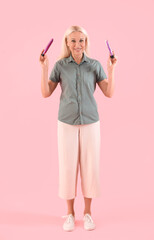 Mature woman with vibrators on pink background