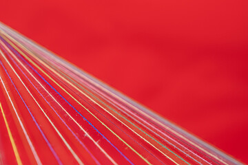 Converging Multi-colored Sewing Thread on a red background