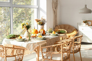 Dining table with autumn setting and pumpkins in room