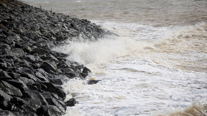 Waves crash on granite stones during a storm on the Black Sea coast. City embankment on a cloudy winter day in Odessa - 763214824