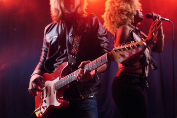 Close up of rock band performing on stage with long haired man playing electric guitar copy space