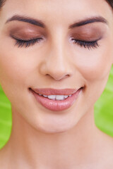 Obraz premium Happy, woman and beauty with makeup, smile and cosmetics with green background. Skincare, wellness and dermatology with a female person and natural skin glow with face treatment and lashes care