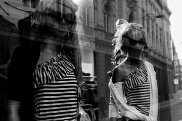 Chic black and white dolls are elegantly displayed in a clothing store window. Ideal for fashion-themed projects and urban lifestyle concepts.