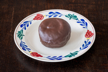 Traditional dutch pastry known as Bossche bol on the plate, chocolate coated ball filled with whipped cream