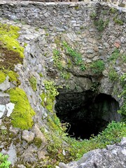 Old stone wall and green moss in the entrance of the cave.