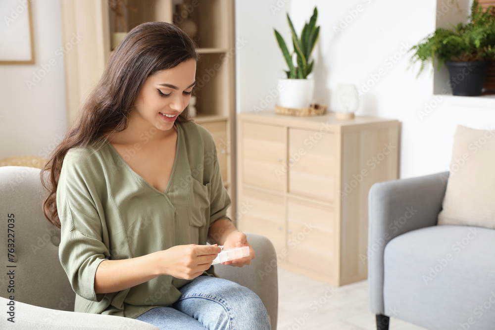 Poster young woman taking pills from daily pill organizer at home