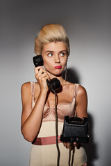 charming young woman with red lipstick puzzled conversation on retro phone in grey background