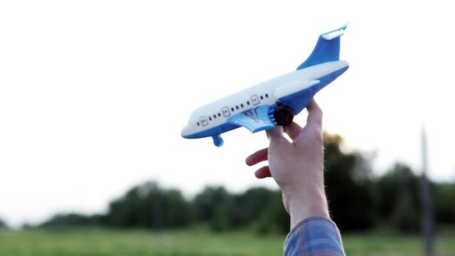 On an agricultural field, a guy holds a model airplane in his hand. A man dreams of becoming an airplane pilot.