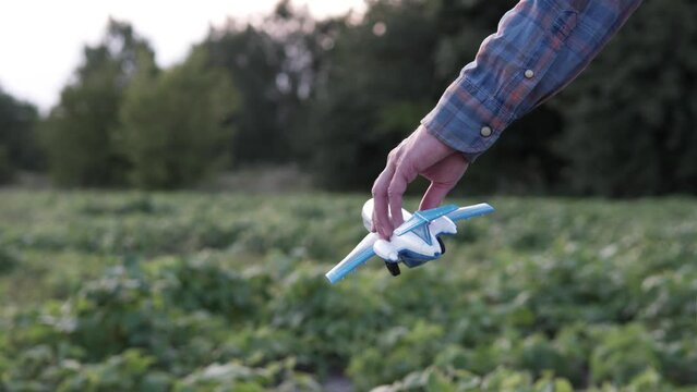 On an agricultural field, a guy holds a model airplane in his hand. A man dreams of becoming an airplane pilot.
