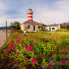 Old lighthouse in Kraljevica in Croatia in summer. Flowers on the foreground.