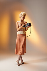stylish girl with blonde hair and red lips calling on retro phone against gray background