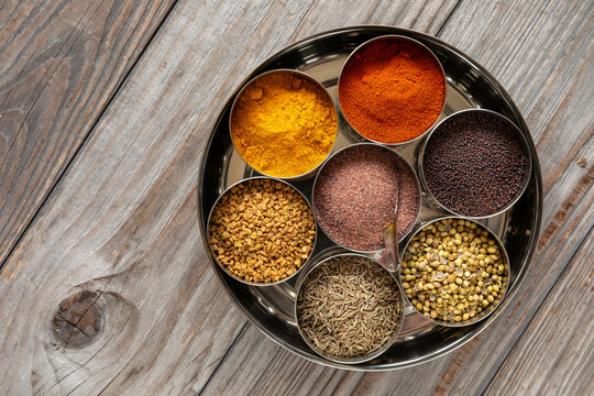 Indian spices box or Indian masala dabba with seven containers on rustic wooden table. Top view. - Powered by Adobe