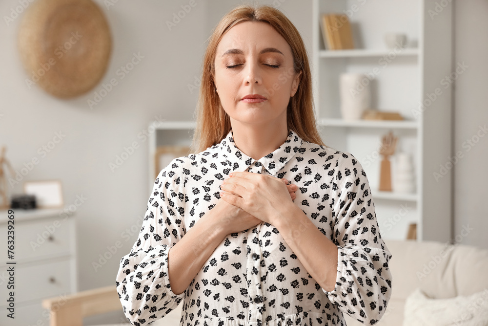 Wall mural Mature woman praying at home