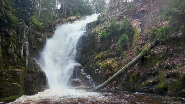 Kamienczyk Rock Waterfall in the Karkonosze Mountains in Poland. Waterfall on a rushing river in a mountain forest among rocks, cascades of rapidly falling boiling and foaming water.