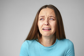 Portrait of displeased upset young woman start crying on gray background