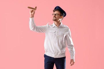 Portrait of male pilot with wooden airplane on pink background