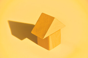 Minimal yellow house made of toy wooden blocks on yellow background. Housing, loan, mortgage,...