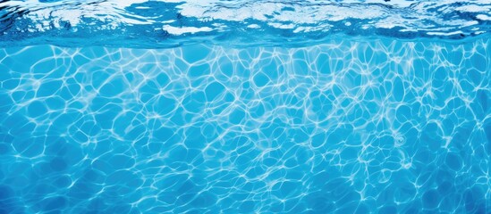 A closeup of the azure liquid in a swimming pool, displaying the fluidity of the water in its electric blue hue. Underwater marine biology in a recreational setting