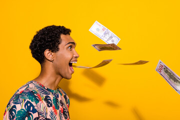 Side profile photo of funny crazy student man open mouth screaming spitting banknotes spend money isolated on yellow color background - obrazy, fototapety, plakaty