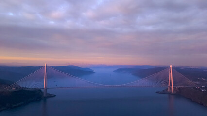 Aerial view of vehicles passing over Istanbul Yavuz Sultan Selim Bridge in sunrise light ships...