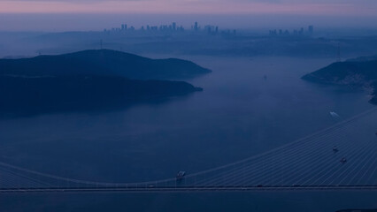 Aerial view of vehicles passing over Istanbul Yavuz Sultan Selim Bridge in sunrise light ships...