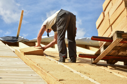 Dachdecker bei der Verlegung der Holzfaserplatten der  Aufsparrendämmung eines Steildachs