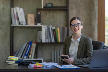 Happy businesswoman using a mobile phone while sitting in an office.