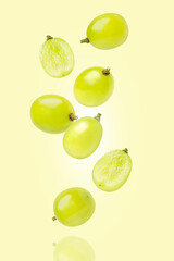 Green muscat grape with half slice flying in the air isolated on green background.