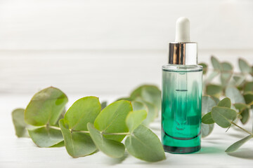 Eucalyptus essential oil in a glass bottle with green eucalyptus leaves on a textured wooden background. Aromatherapy concept. Spa. Natural organic ingredients for cosmetics and body care.Copy space